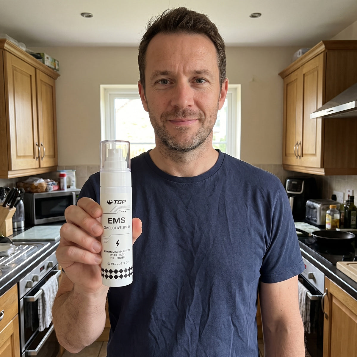 Man holding the TGP EMS Conductive Spray in his kitchen